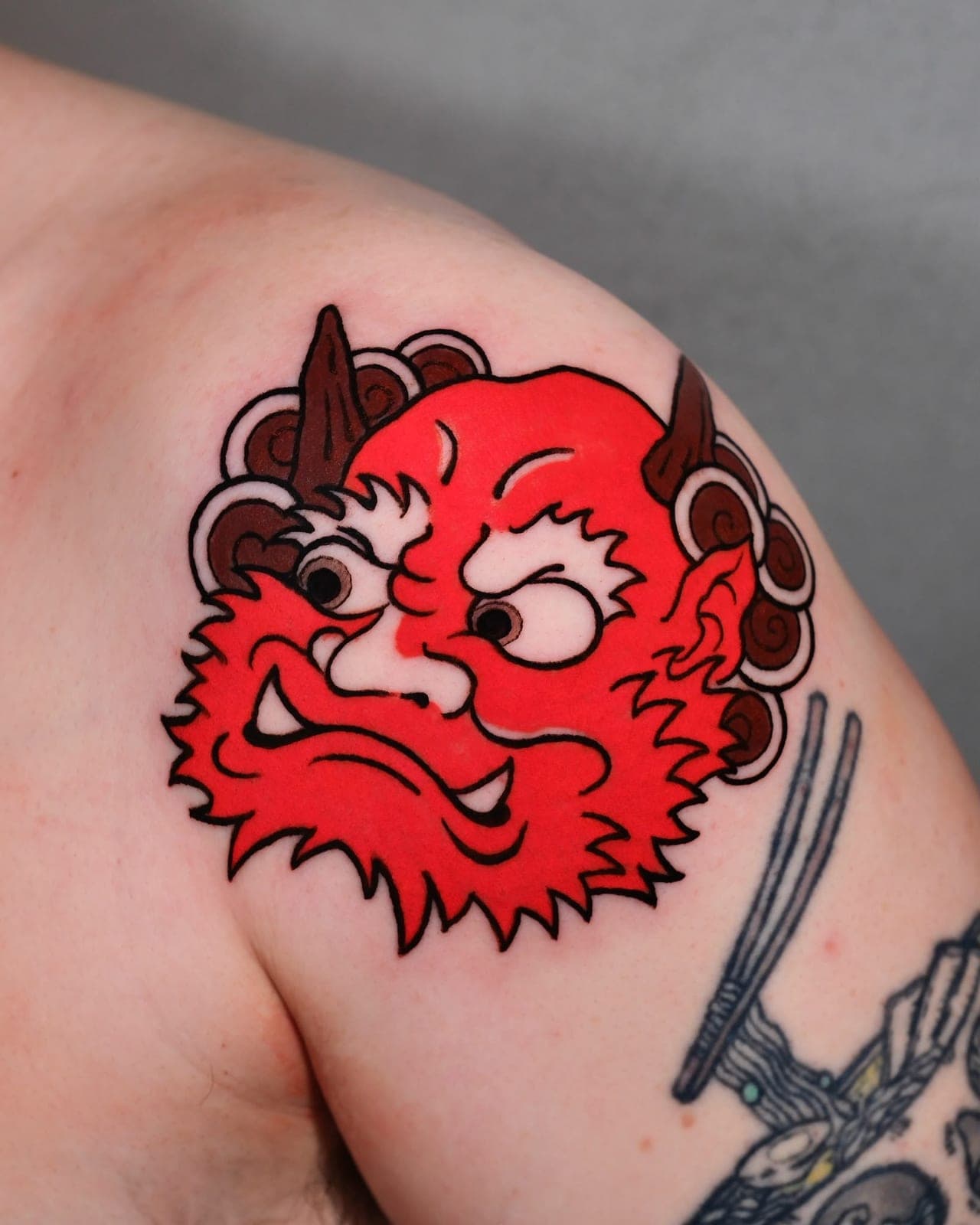 Red oni mask tattoo on the shoulder