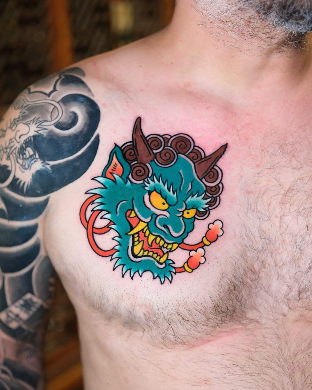 Japanese Wabori-style blue demon mask tattoo on the chest