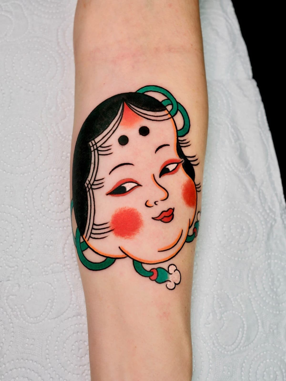 Japanese Okame mask tattoo on the forearm