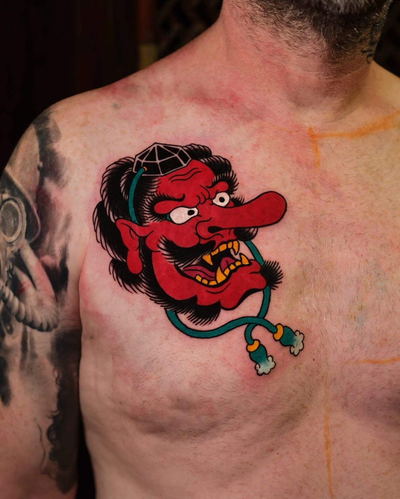 Red tengu mask tattoo on the chest