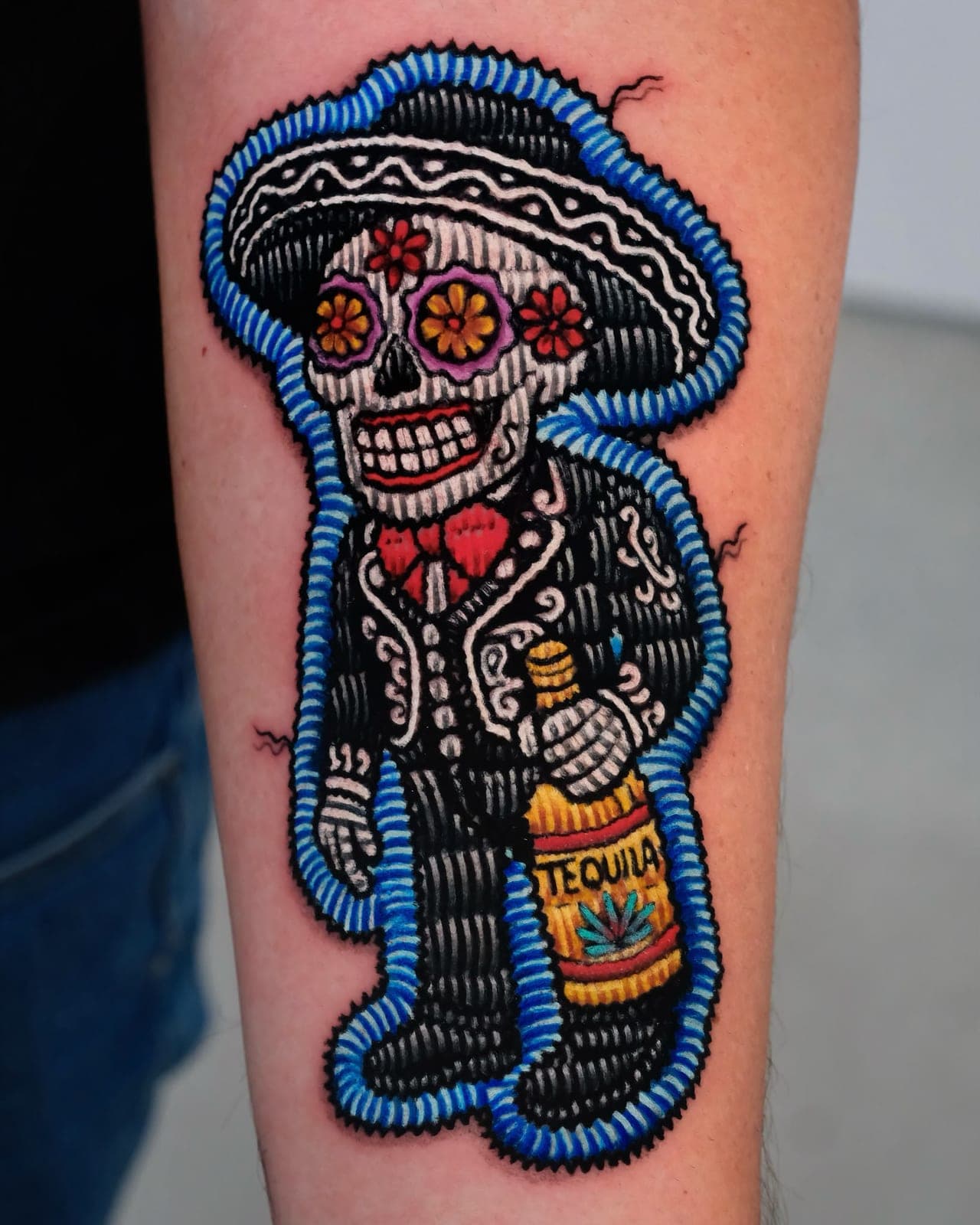Embroidered-patch style tattoo of a Day of the Dead mariachi skeleton with a tequila bottle