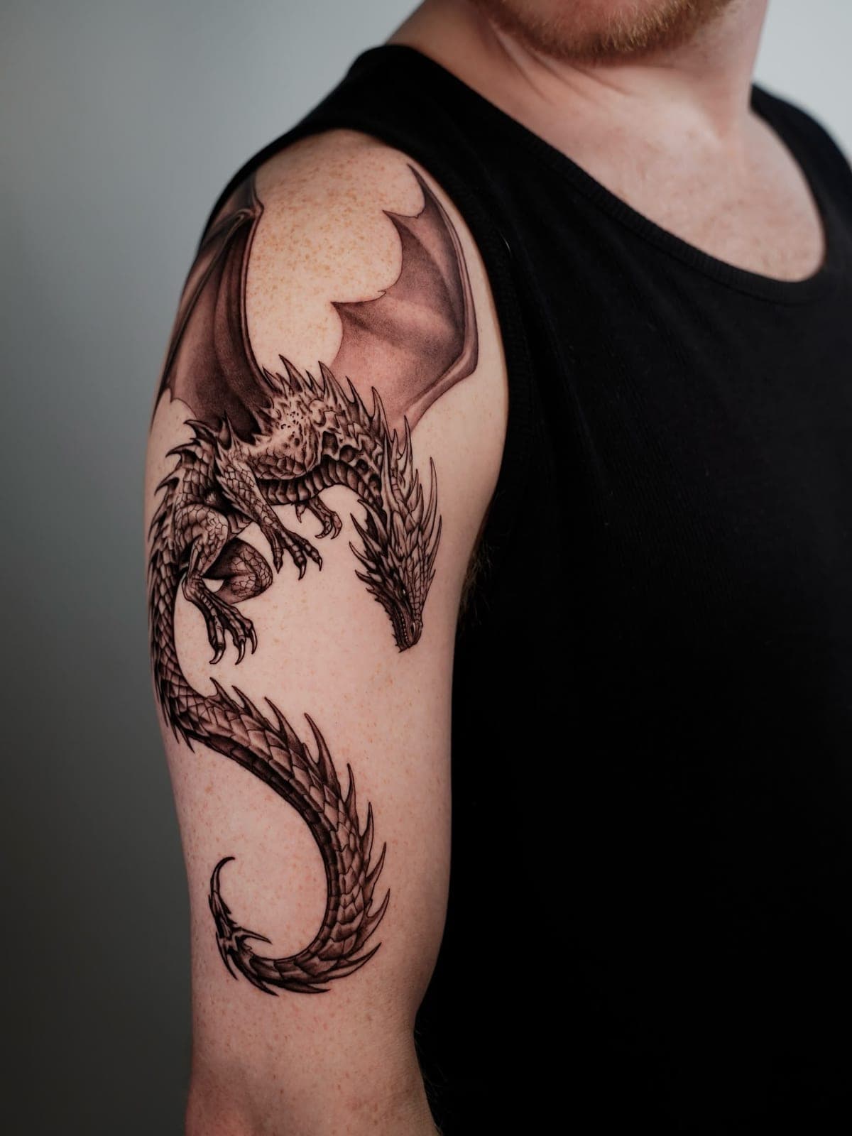 Black and grey dragon wrapping around the upper arm