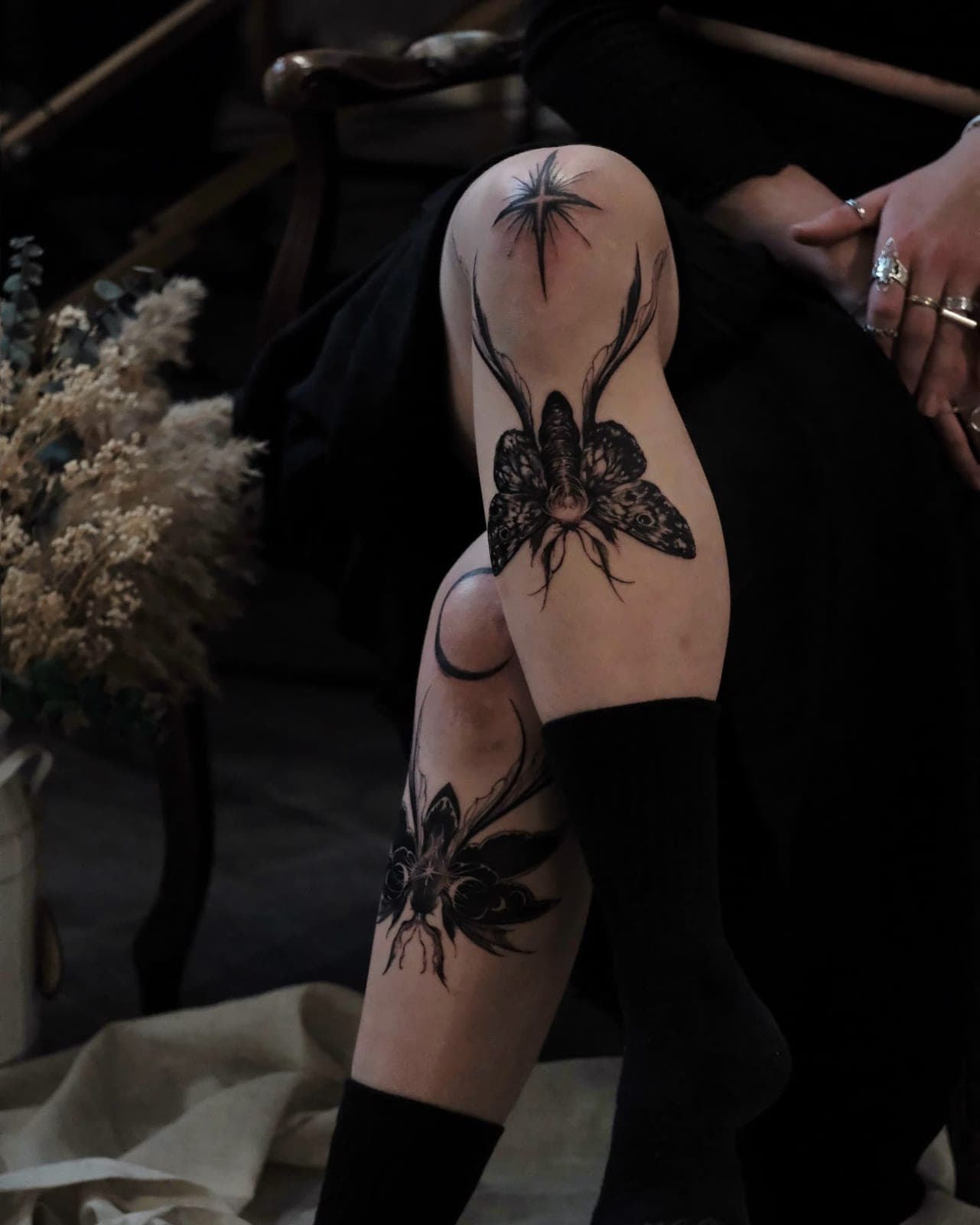 Blackwork moth on the knee with a flower below