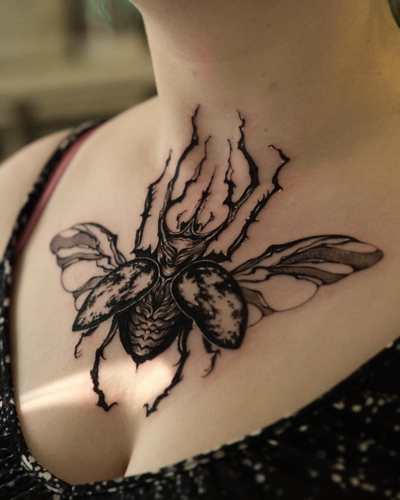 Blackwork beetle with spread wings across a client's chest