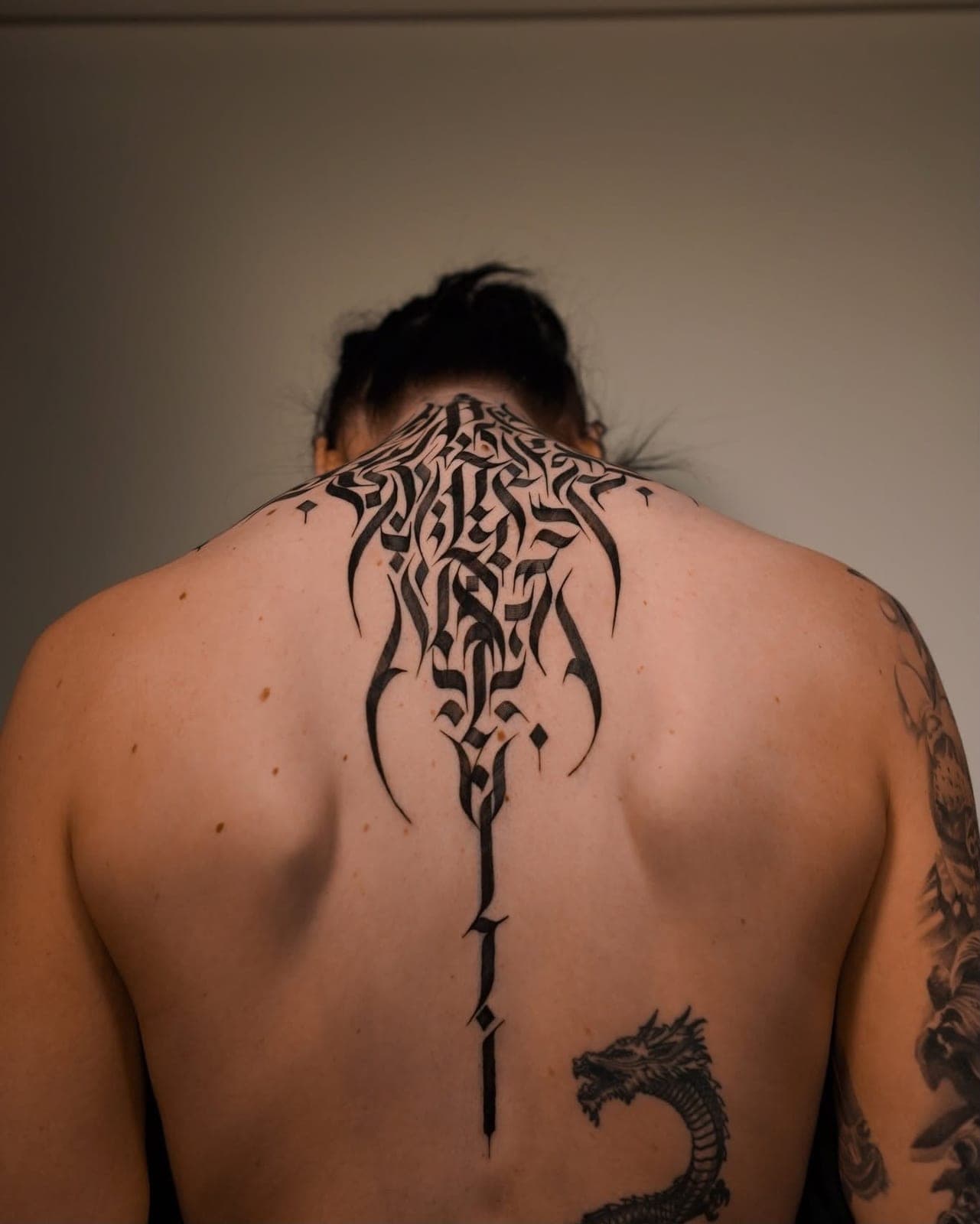 Calligraphy tattoo running down the length of a spine