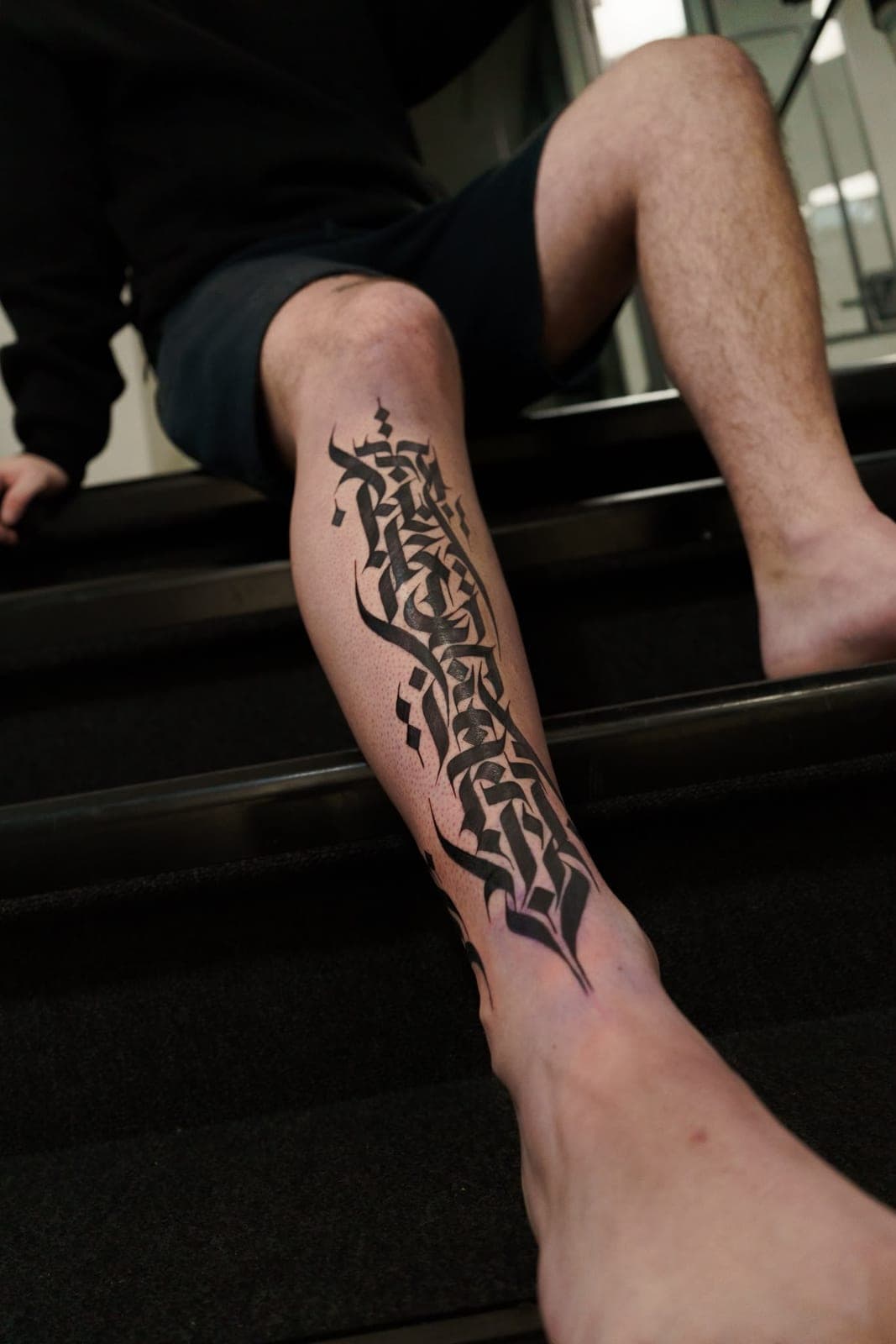 Vertical calligraphy tattoo on a shin
