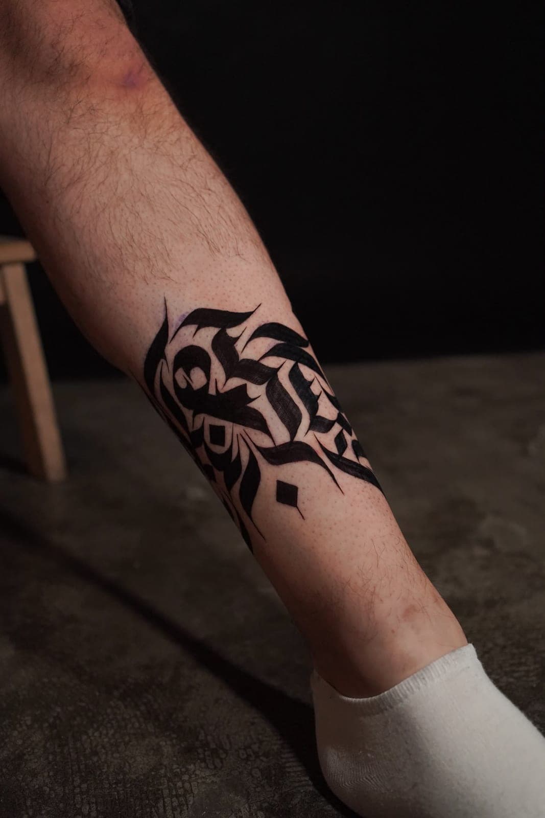 Calligraphy tattoo wrapping around a calf