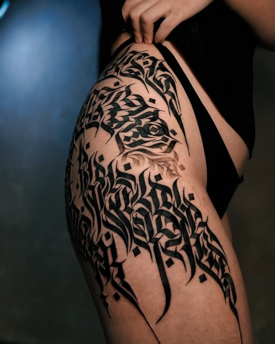 Large calligraphy piece across the hip and thigh