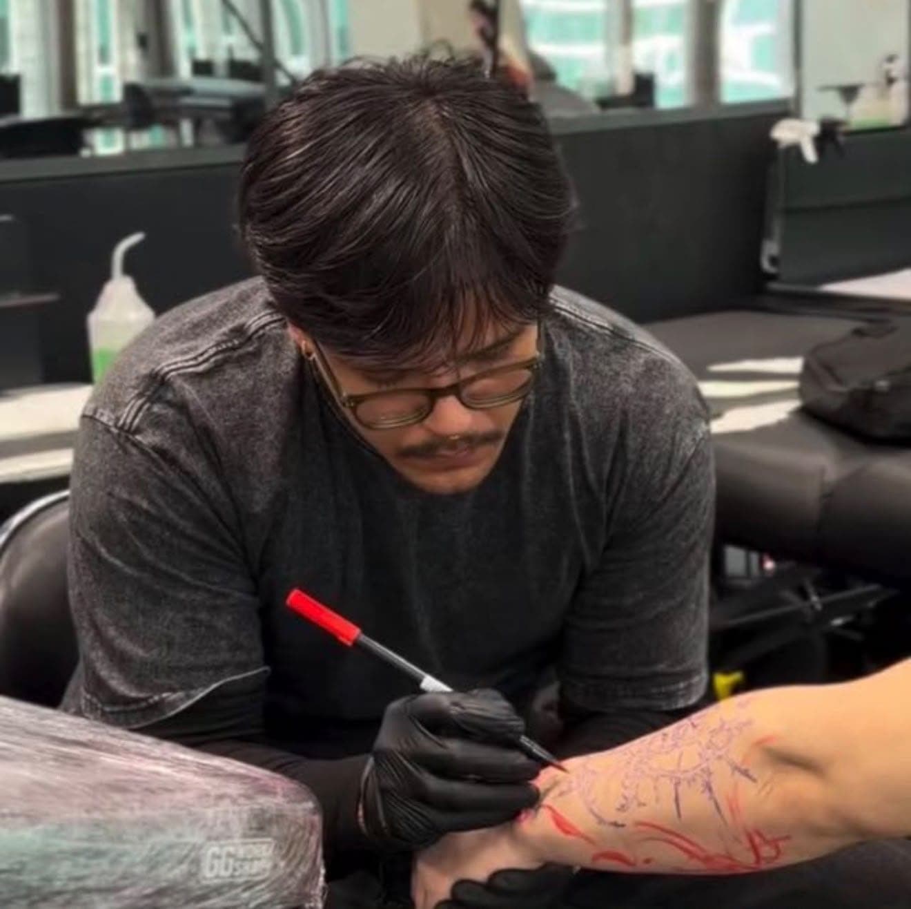 Toni Xavier drawing a stencil design on a client's arm