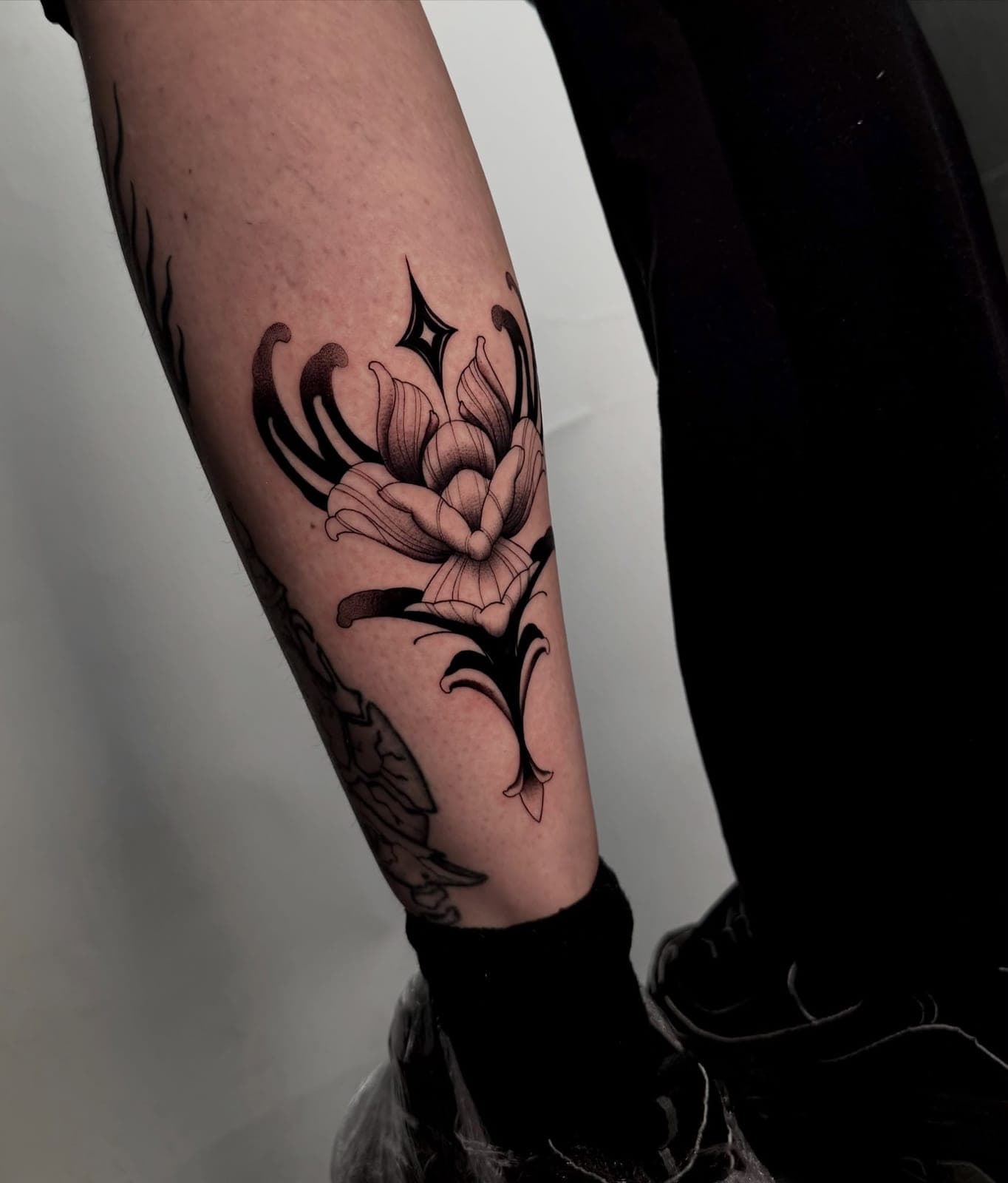 Blackwork flower with ornamental shapes on the calf