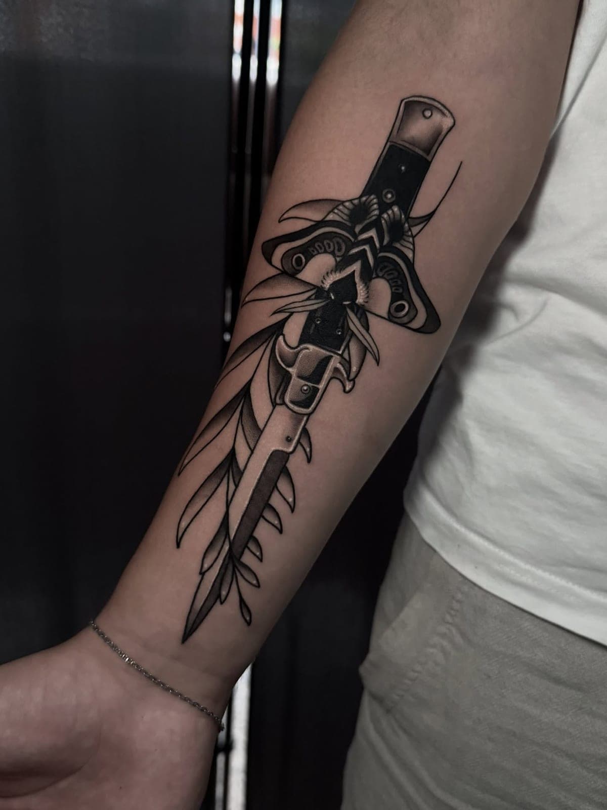Blackwork dagger and moth on the forearm